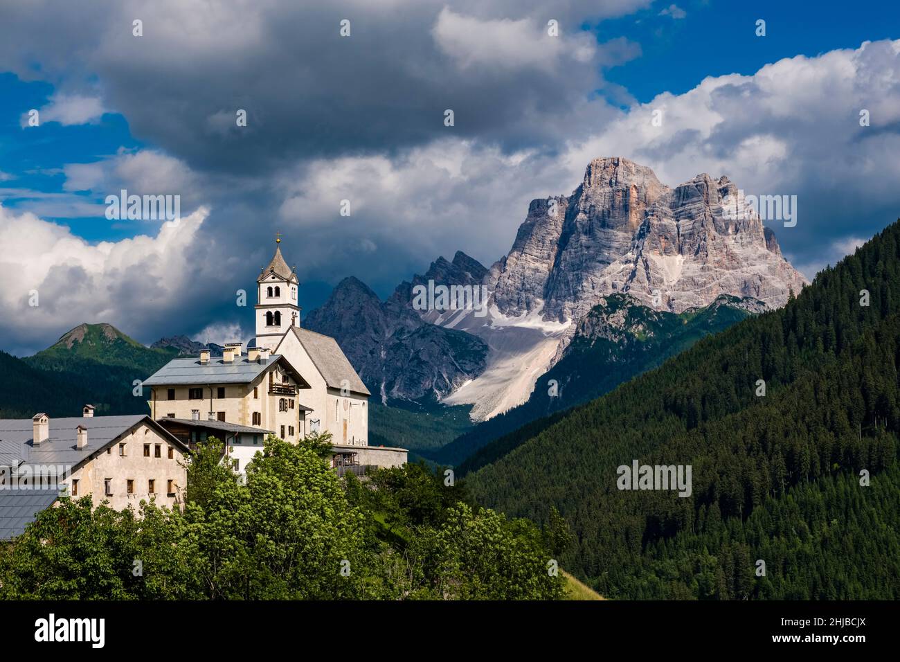 The church Chiesa Santa Lucia in Colle Santa Lucia at the foot of Giau Pass, Passo di Giau, the summit of Monte Pelmo in the distance. Stockfoto