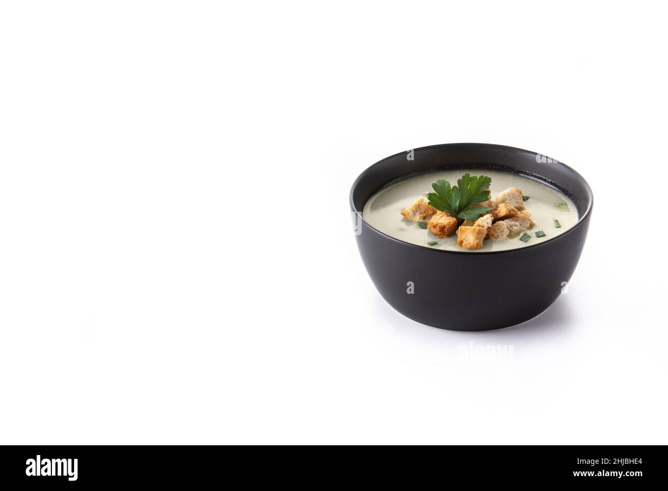 Knoblauchsuppe garniert mit Croutons in schwarzer Schüssel isoliert auf weißem Hintergrund Stockfoto