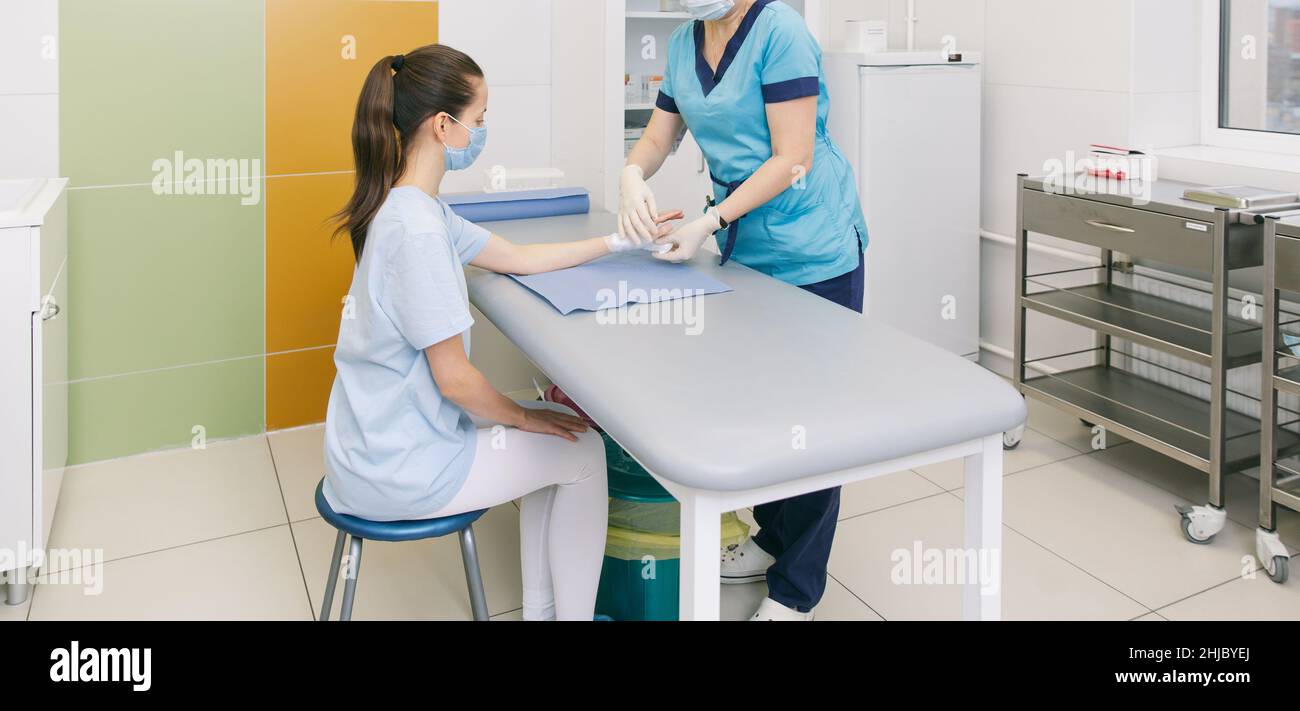 Ein Arzt wickelte sich um das Handgelenk, um die erste-Hilfe-Nahaufnahme zu machen. Anwendung von Verbänden auf die Hände des Patienten, erste-Hilfe-Konzepte und Verletzungen des Handgelenks Stockfoto