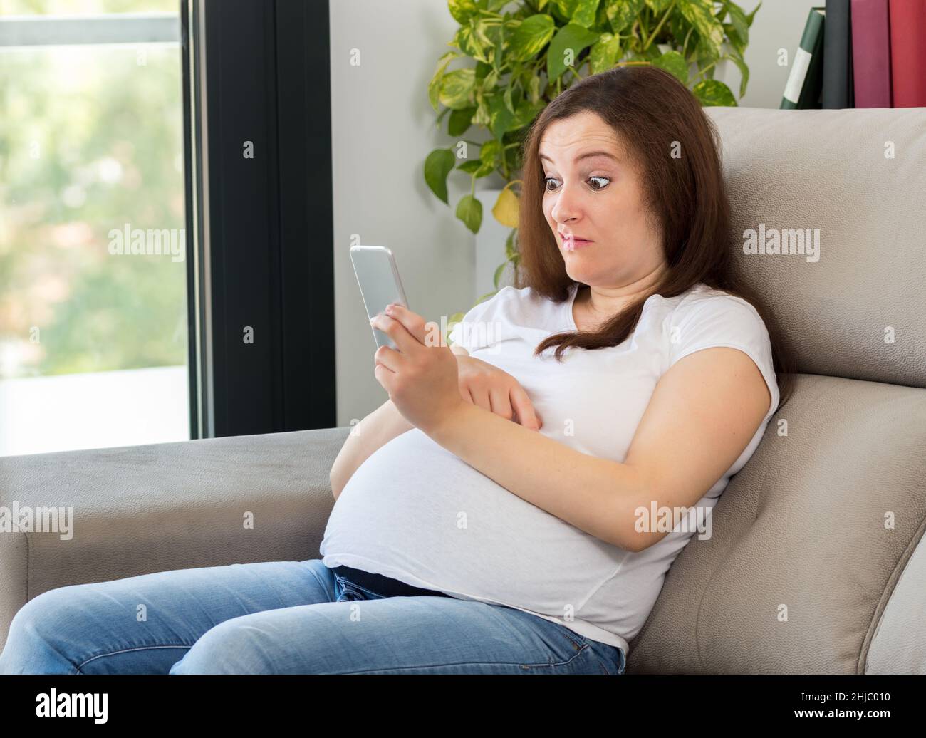 Verwirrte Frau, die zu Hause die Nachricht am Telefon ansieht Stockfoto