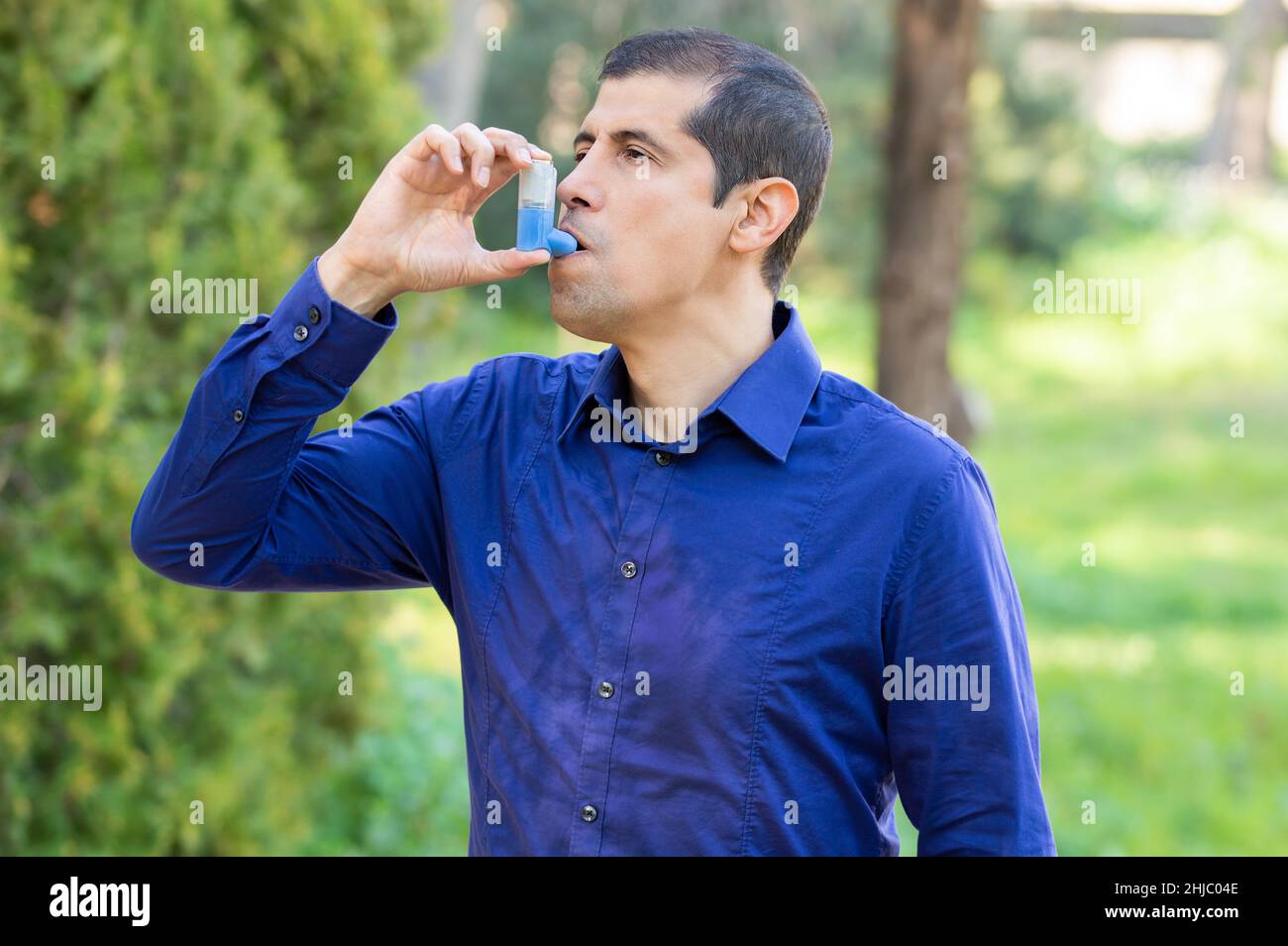 Der Mensch verwendet einen Asthmainhalator in einem Park Stockfoto