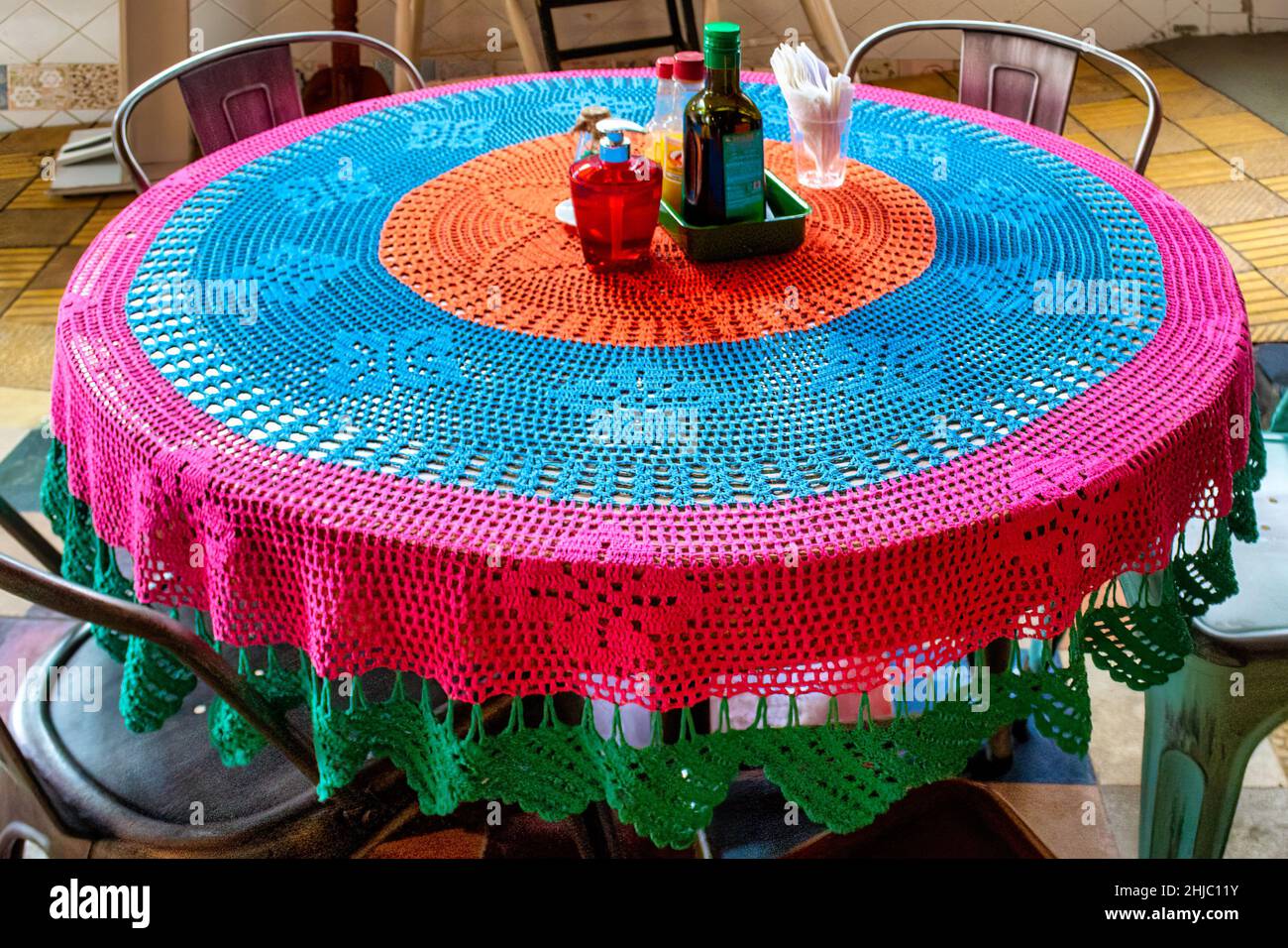 Mehrfarbige gestrickte Tischdecke in einem privaten rustikalen Restaurant in der Stadt. Stockfoto