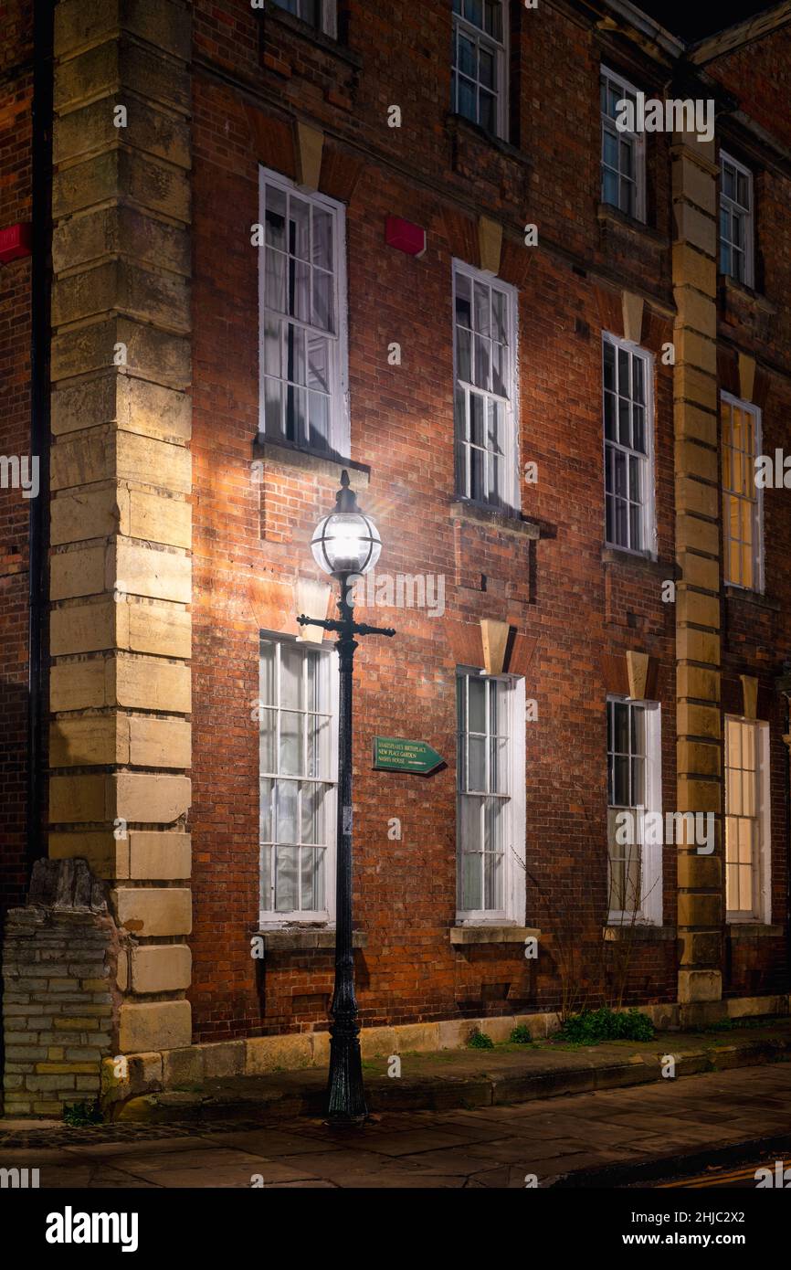 Das alte Gebäude der Trinity College-Schule und der Lampenpfosten entlang der Church Street bei Nacht. Stratford-Upon-Avon, Warwickshire, England Stockfoto