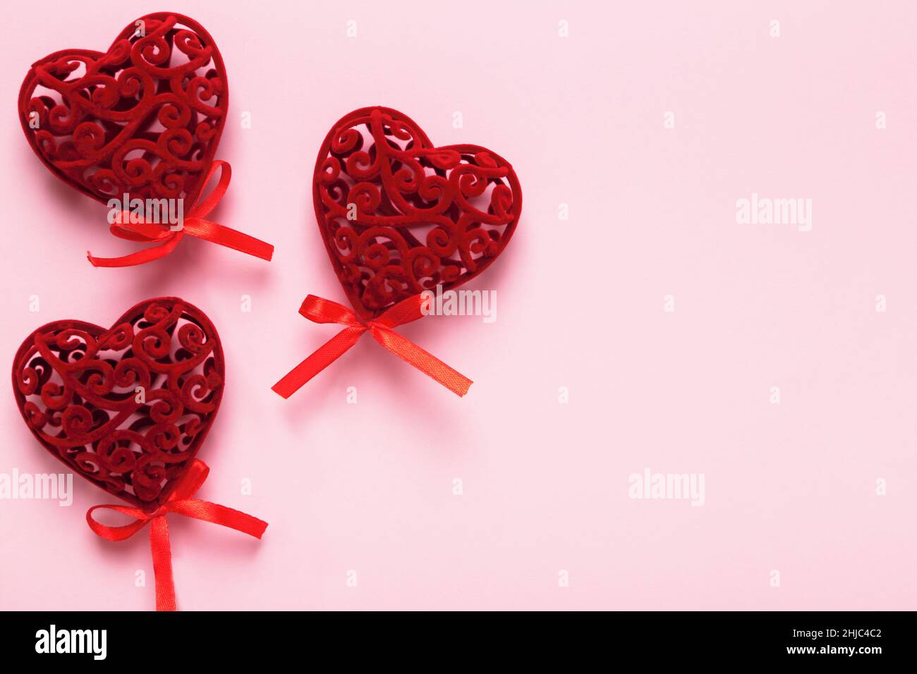 Drei rote valentinsherzen auf einem rosa Hintergrund mit Kopierfläche. Stockfoto