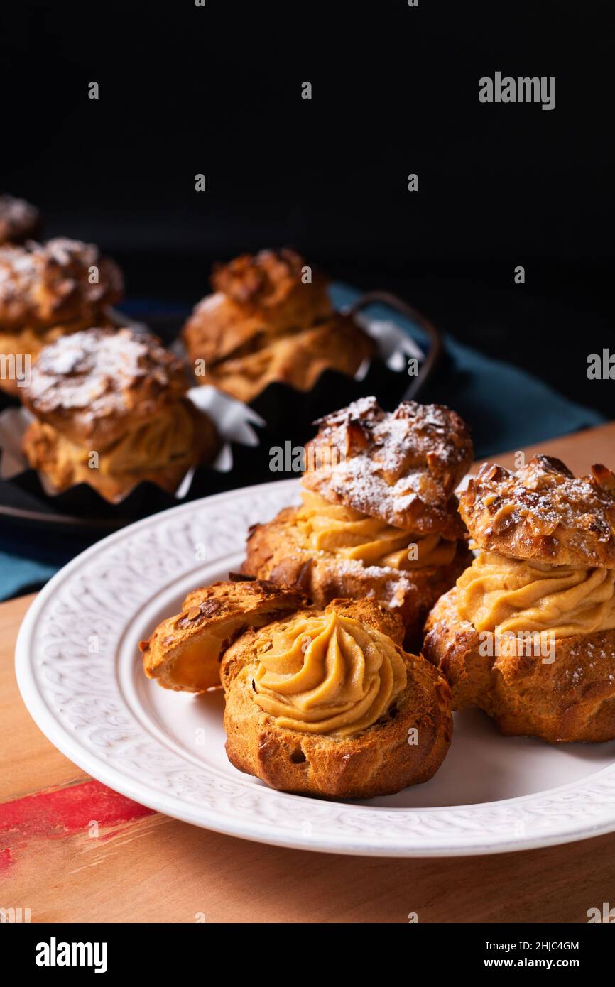 Lebensmittelkonzept hausgemachte Caramel Choux a la Cream oder Choux Cream Puffs auf dunklem Hintergrund mit Kopierfläche Stockfoto