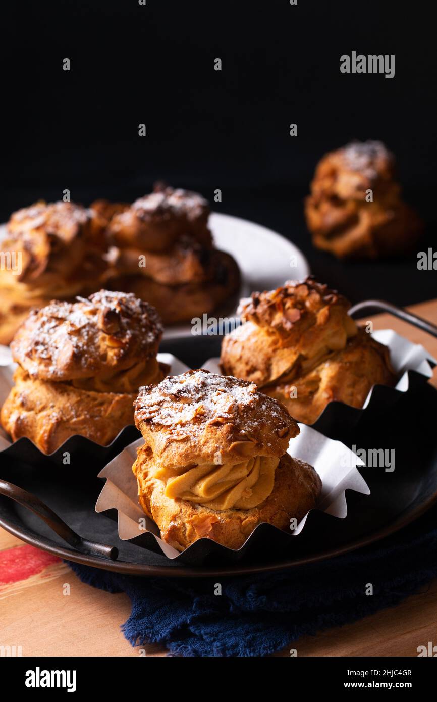 Lebensmittelkonzept hausgemachte Caramel Choux a la Cream oder Choux Cream Puffs auf dunklem Hintergrund mit Kopierfläche Stockfoto