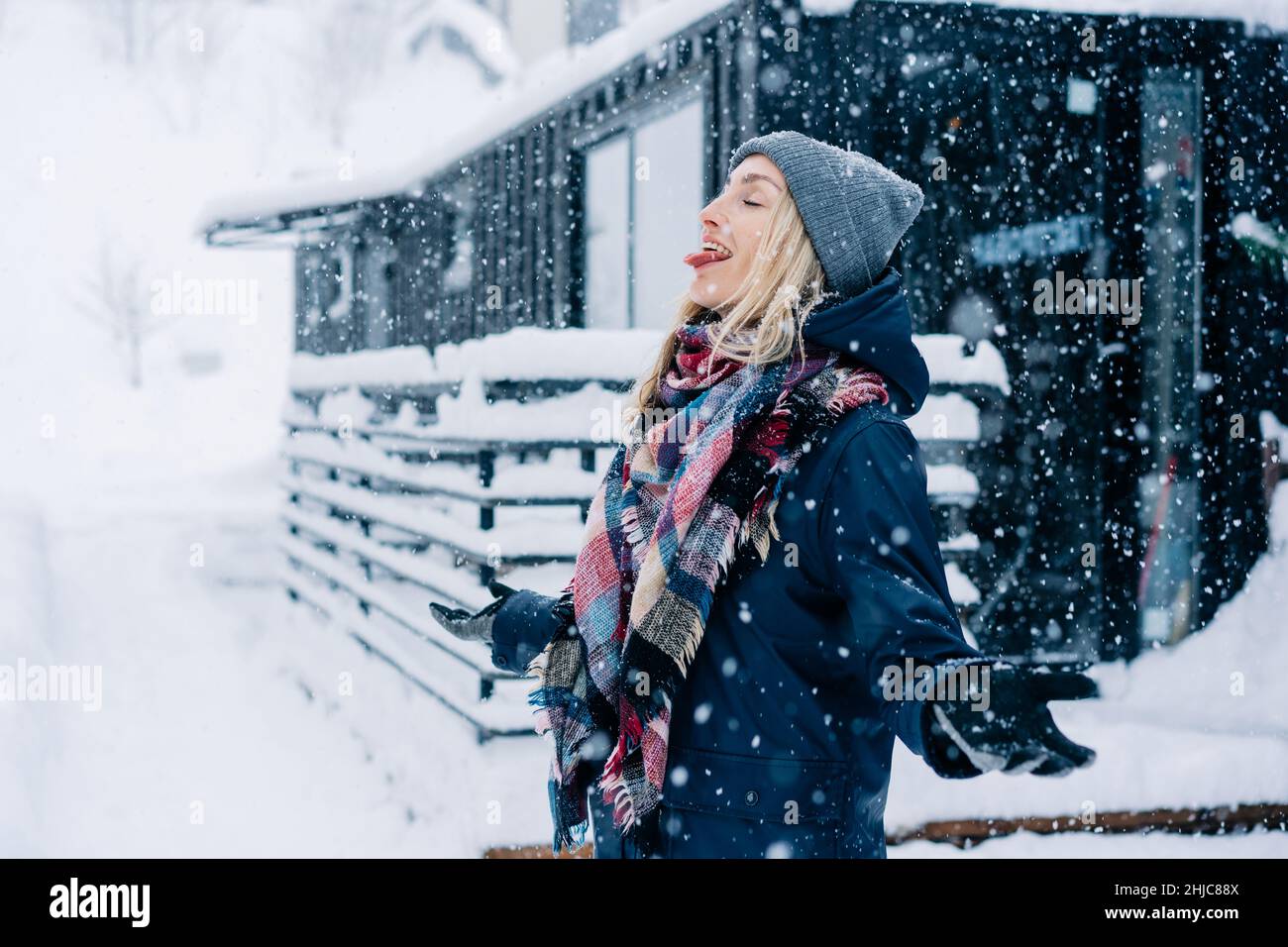 Eine junge Frau streckt ihre Zunge aus, um während eines Schneesturms Schneeflocken zu fangen. Stockfoto