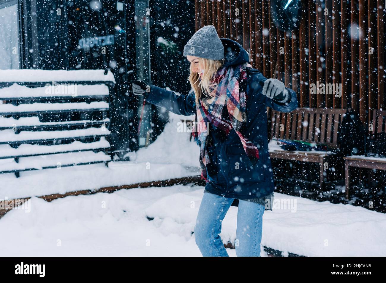 Eine junge Frau hat Spaß und freut sich, als Kind bei einem Schneefall zu springen. Stockfoto
