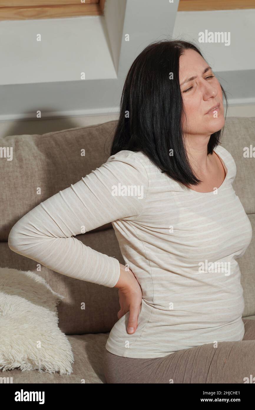 Ältere Frau mittleren Alters, die zu Hause an Rückenschmerzen und Flankenschmerzen leidet. Muskelprobleme, Nierensteine oder Gallenblasenerkrankungen. Symptome von Krankheit o Stockfoto