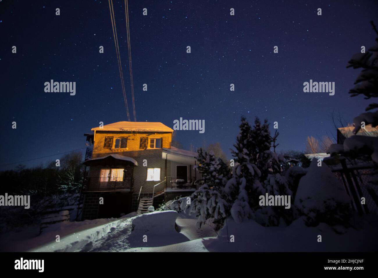 Holzhaus mit einem Licht in den Fenstern. Nachtlandschaft im Winter. Stockfoto