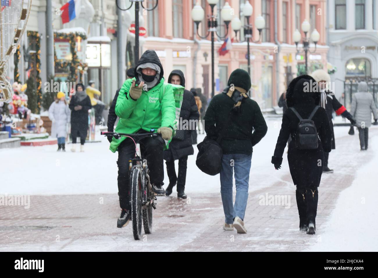 Moskau, Russland. 28th Januar 2021. Im Winter fährt ein Mitarbeiter der  Lebensmittelzustellung in einer Gesichtsmaske in der Arbat Street mit dem  Fahrrad. Seit dem 26. Januar 2022 ist die Zahl der neuen