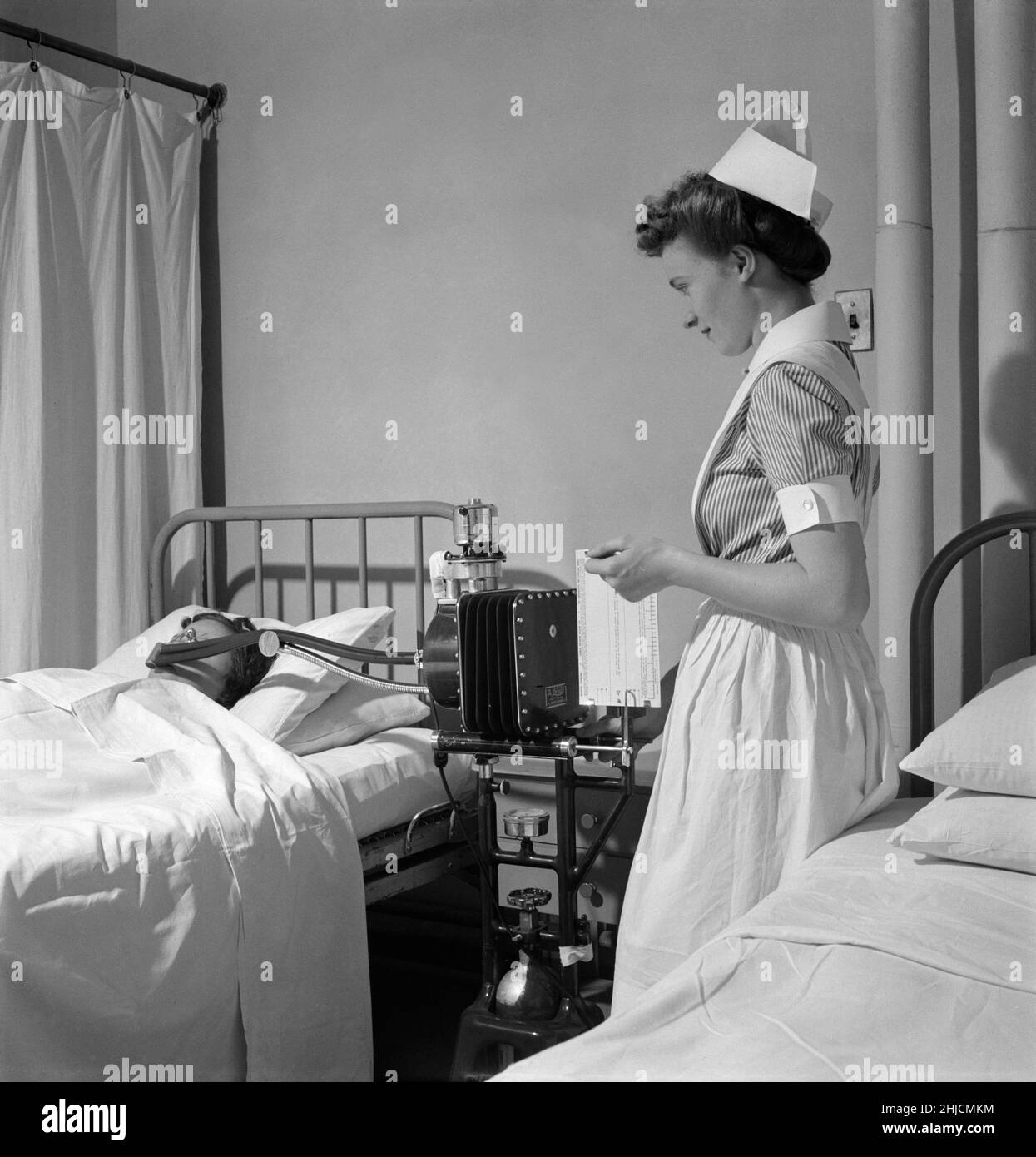 Eine Krankenschwester in einem Krankenhaus, die einem Patienten einen Stoffwechseltest gibt. Fotografiert von Fritz Henle (1909-1993) im November 1942. Stockfoto