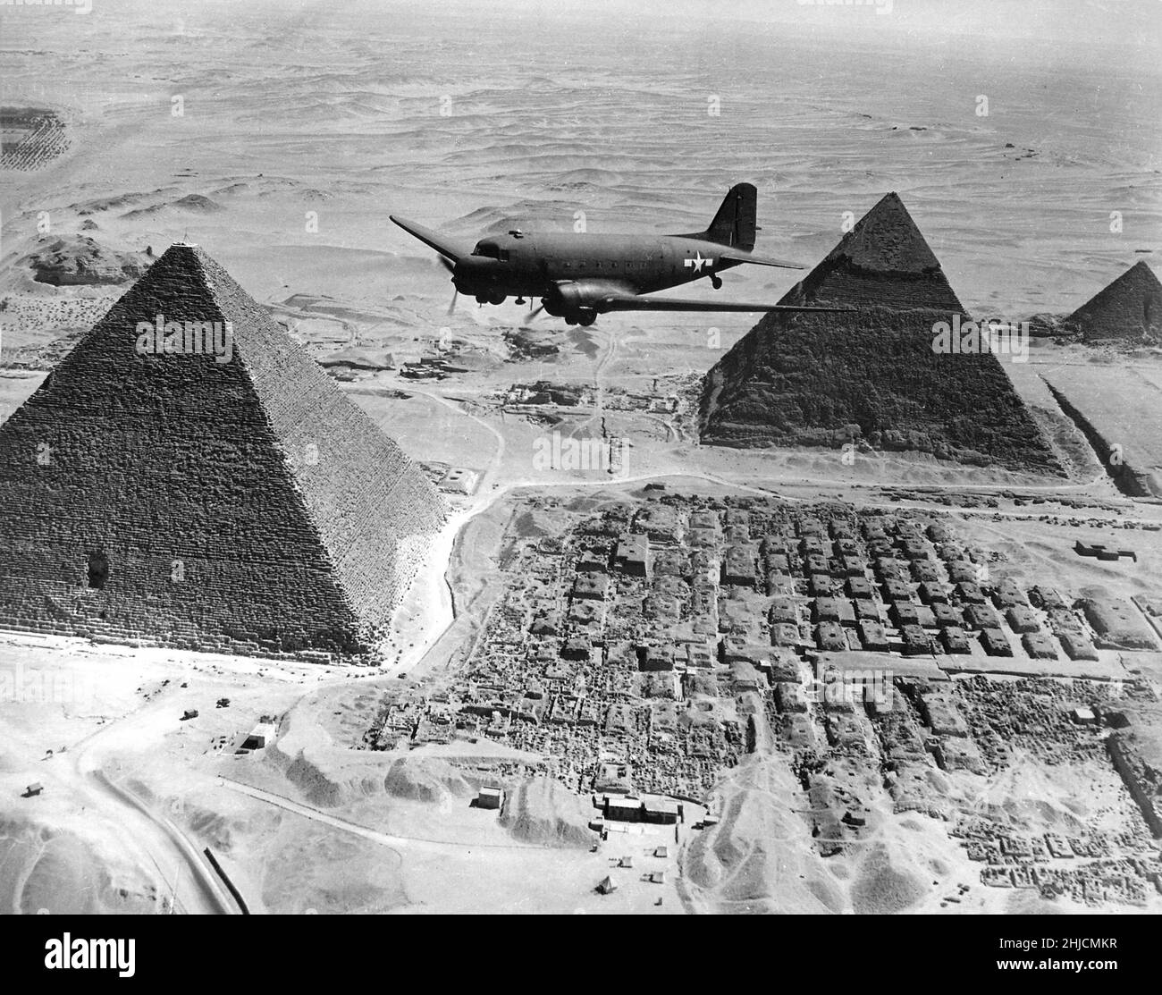 Ein US Army Air Forces Air Transport Command Douglas C-47 Skytrain, der während des Zweiten Weltkriegs 1943 über die Pyramiden von Gizeh in Ägypten fliegt. Dieses Flugzeug, das mit dringenden Kriegsvorräten und -Materialien beladen war, gehörte zu einer Flotte, die von den USA über den Atlantik und Afrika in strategische Kampfgebiete verschiffte. Stockfoto