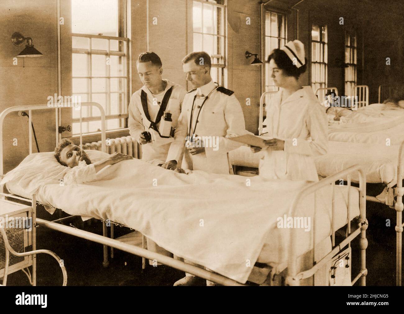 Ein Patient in einer Abteilung des US Naval Hospital, Chelsea, Massachusetts. Ein Chirurg, eine Krankenschwester und ein Korpsmann untersuchen einen Patienten in der Abteilung 6, Gruppe 1, 2. Juni 1919. Marine History and Heritage Command Foto. Stockfoto
