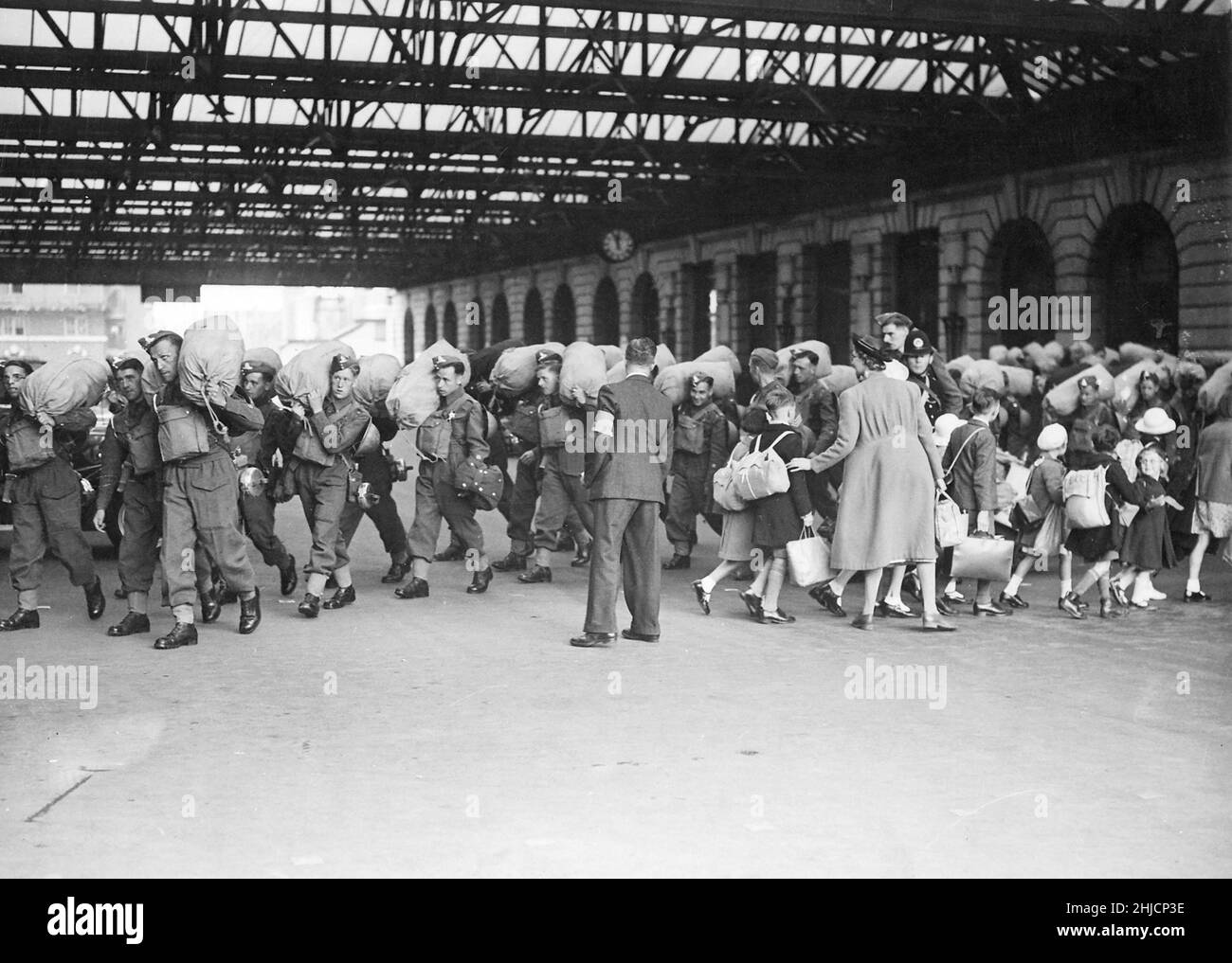 Truppen kommen an einem Londoner Bahnhof an, während Kinder während des Blitzes, des 2. Weltkriegs 1940, auf das Land evakuieren. Stockfoto