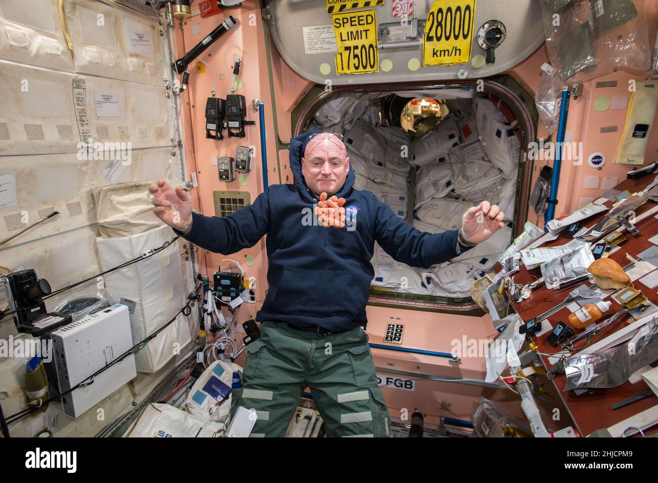 Snack-Zeit auf der Internationalen Raumstation, während NASA-Astronaut Scott Kelly während der Expedition 43 im April 2015 einen Haufen frischer Karotten vor ihm schweben sieht. Scott ist eines der einjährigen Crewmitglieder auf der Station, um zu testen, wie der menschliche Körper auf eine ausgedehnte Präsenz im Weltraum reagiert, als Vorbereitung auf die langen Flüge, die die NASA zum Mars und zurück in die Zukunft plant. Stockfoto