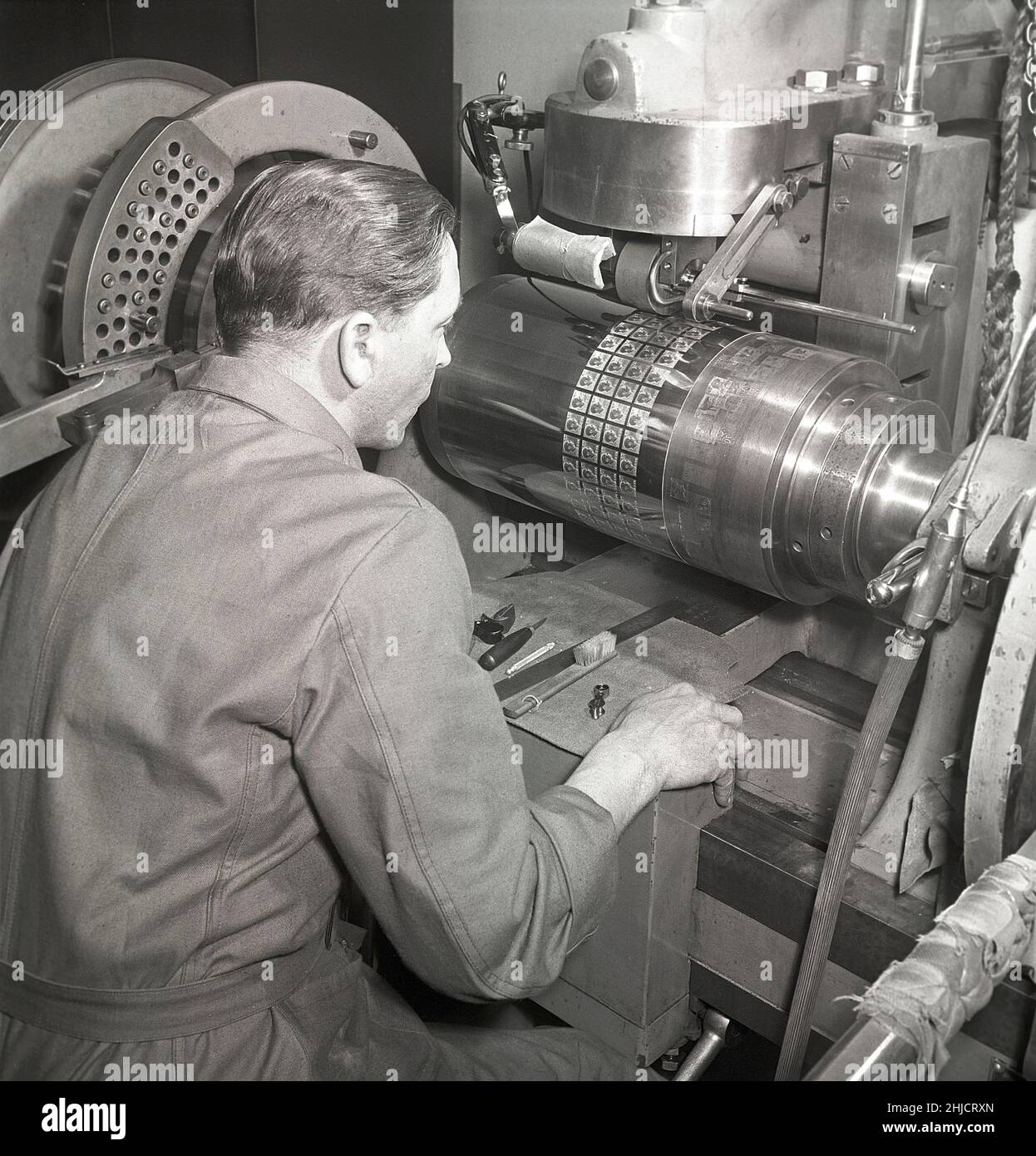 Herstellung von Briefmarken in der 1950s. Ein Mann mit der Maschine, die den Druckzylinder macht, der später zum Drucken der Stempel der neuen Gustaf Adolf-Marken verwendet wird. Insgesamt sind 340 Stempelgravuren negativ auf den Zylinder montiert. Schweden 1951 Kristoffersson Ref. bc45-11 Stockfoto