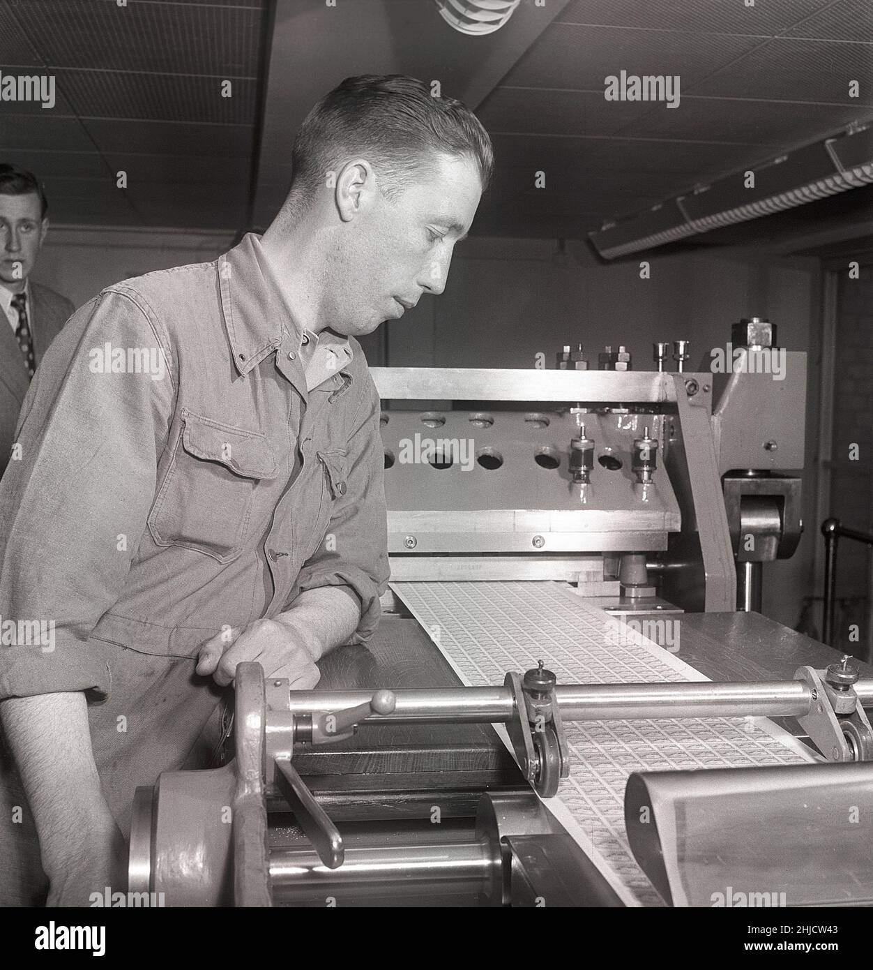 Herstellung von Briefmarken in der 1950s. Ein Manat der schwedischen Briefmarkendruckwerke der schwedischen Post übersieht das Verfahren der neu gedruckten Gustaf VI Adolf-Marken, wenn sie zu einzelnen Marken mit nur dünnen Papierstücken ferforiert werden, die das Briefmarkenblatt zusammenhalten. Schweden 1951 Kristoffersson Ref. bc44-11 Stockfoto