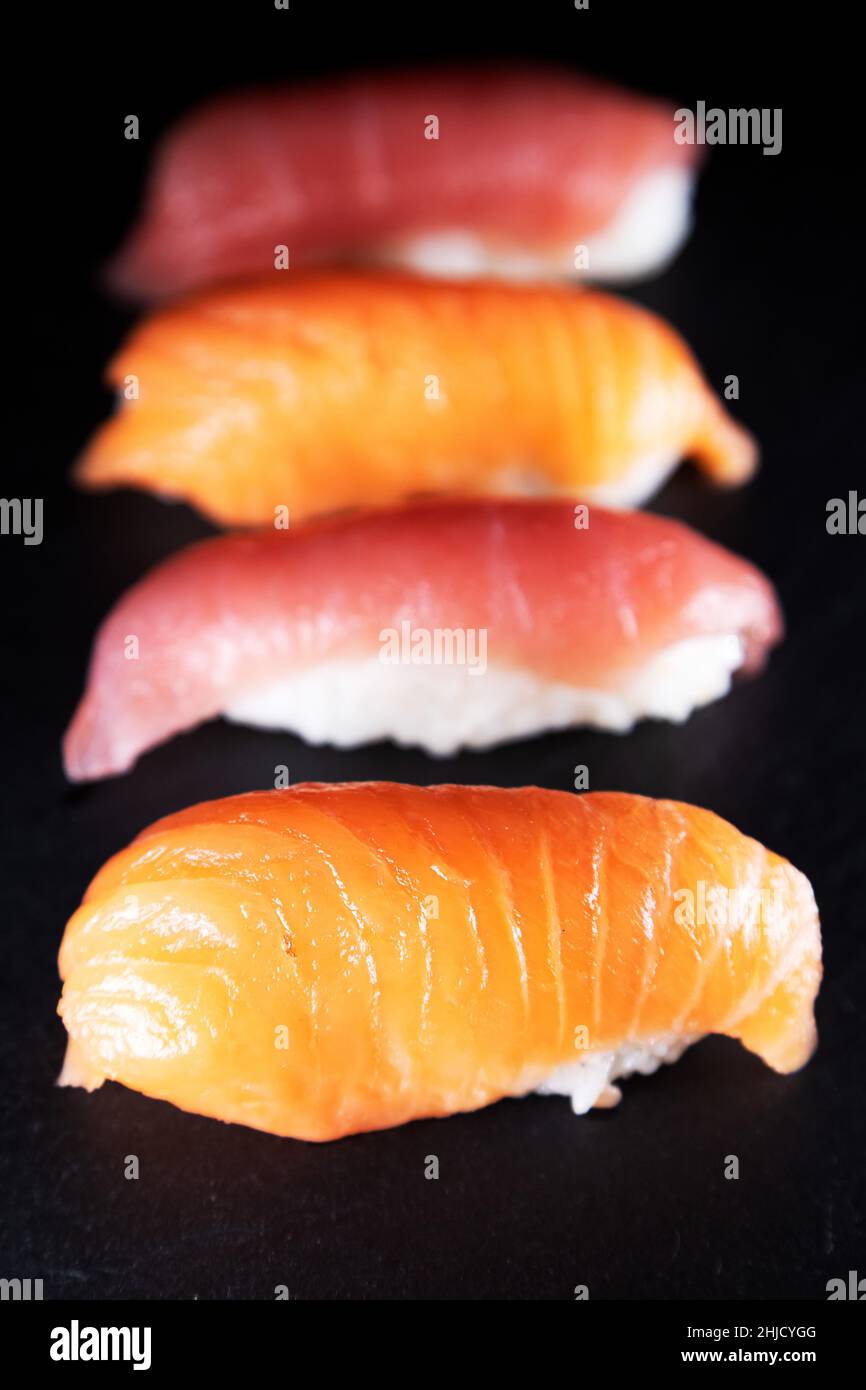 Eine Platte mit Thunfisch und Lachs Nigiri. Sushi-Sorten, das Gericht stammt aus Japan und besteht aus dünn geschnittenem rohem Fisch, der über weißem Reis mit gemischtem Witz serviert wird Stockfoto