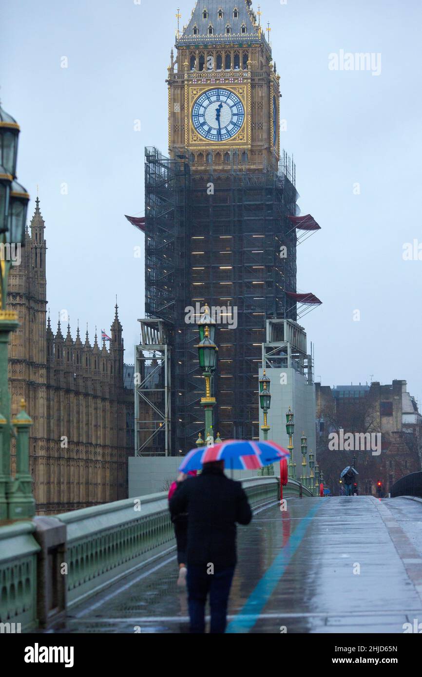 Der Elizabeth Tower, der gemeinhin als Big Ben bekannt ist, wird als Fußgänger angesehen, der einen Regenschirm mit der Unionsflagge auf der Westminster Bridge im Zentrum Londons hält. Stockfoto