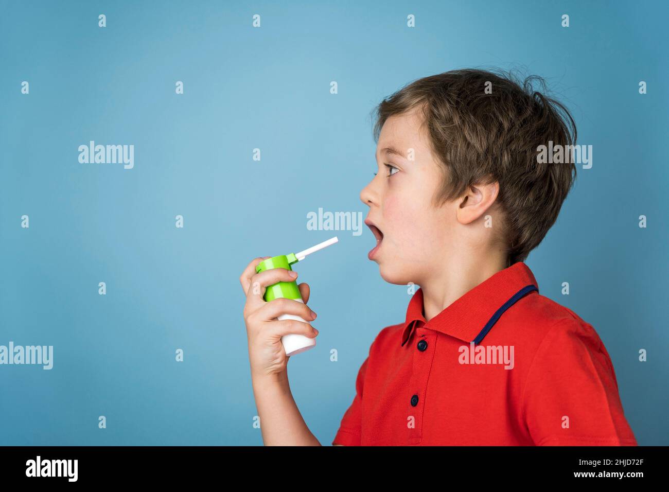 Ein süßer 5-jähriger kaukasischer Junge in einem roten T-Shirt sprüht ein Aerosol in seinen Mund, um Halsschmerzen zu behandeln, Spray für den topischen Gebrauch. Aerosol-Inhalator. Krank c Stockfoto