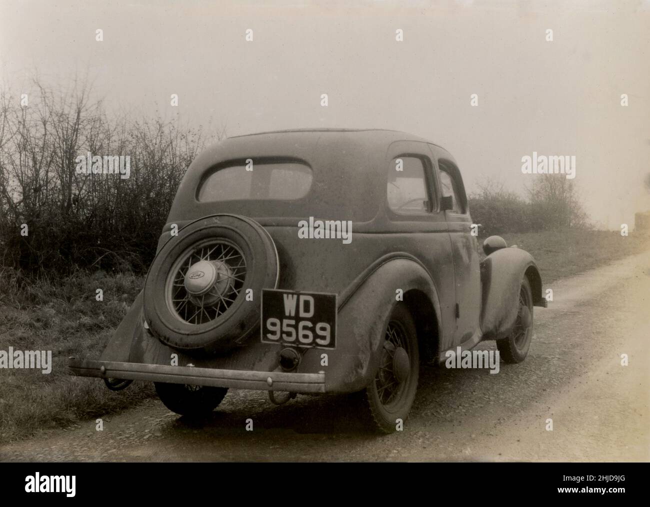 1940s, historisch, am frühen Morgen und ein schlammiger Ford Modell C Ten, geparkt auf einer Spur an einer Hecke, Essex, England, Großbritannien. Das Auto wurde zwischen 1934 und 1937 in Großbritannien hergestellt, wobei die „zehn“ sich auf seine 10 britischen fiskalischen PS beziehen. Stockfoto