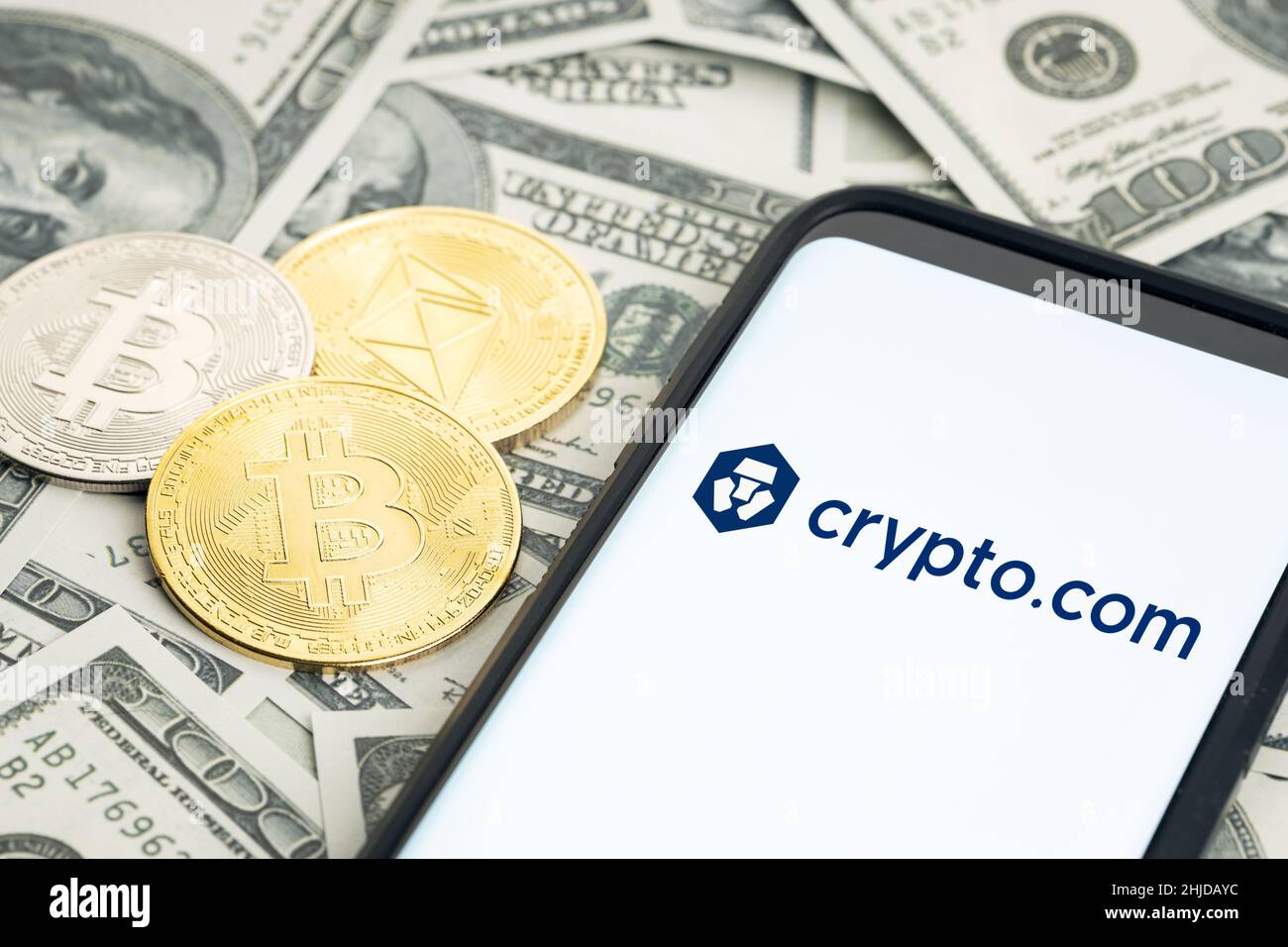 Galicia, Spanien; 28. januar 2022: Smartphone-Bildschirm mit Crypto.com Logo- und Dollar-Banknoten sowie Bitcoin- und ethereum-Münzen Stockfoto