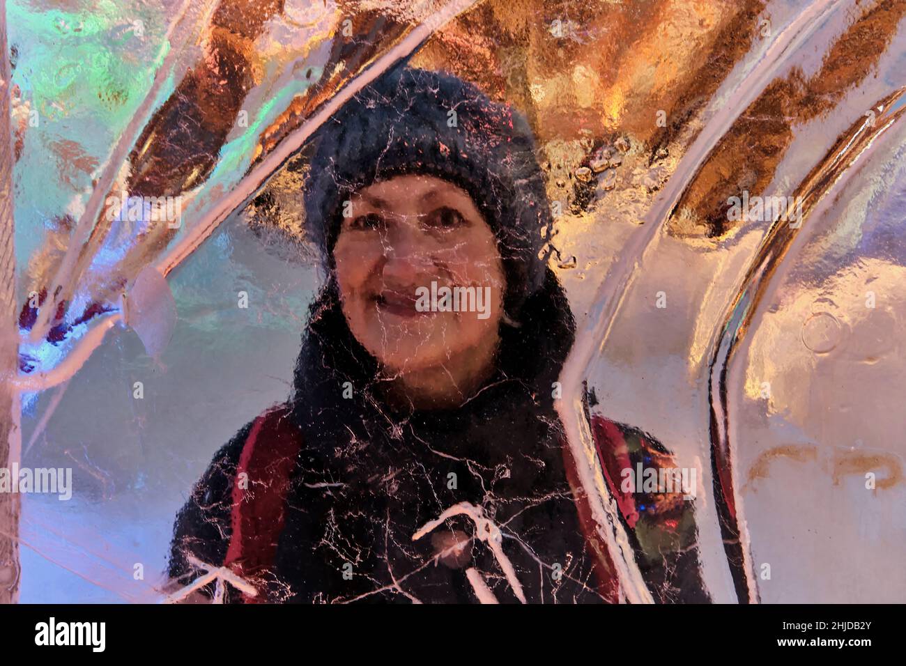 Kreatives Winterporträt über der Eiswand der glücklichen lächelnden älteren Frau. Stockfoto