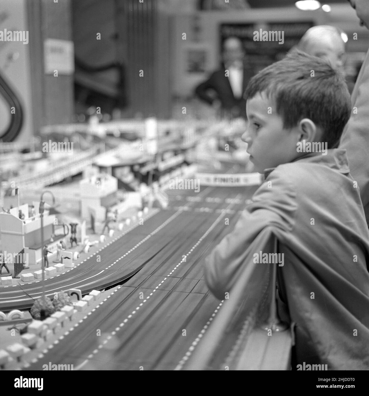 Spielzeug in der 1960s. Ein Junge fasziniert von einer Miniatur-Rennstrecke von Scalextric. Man konnte Autos mit einer Fernbedienung fahren und gegeneinander antreten, da es das war, worum es im Spiel ging. Schweden 1962 Stockfoto