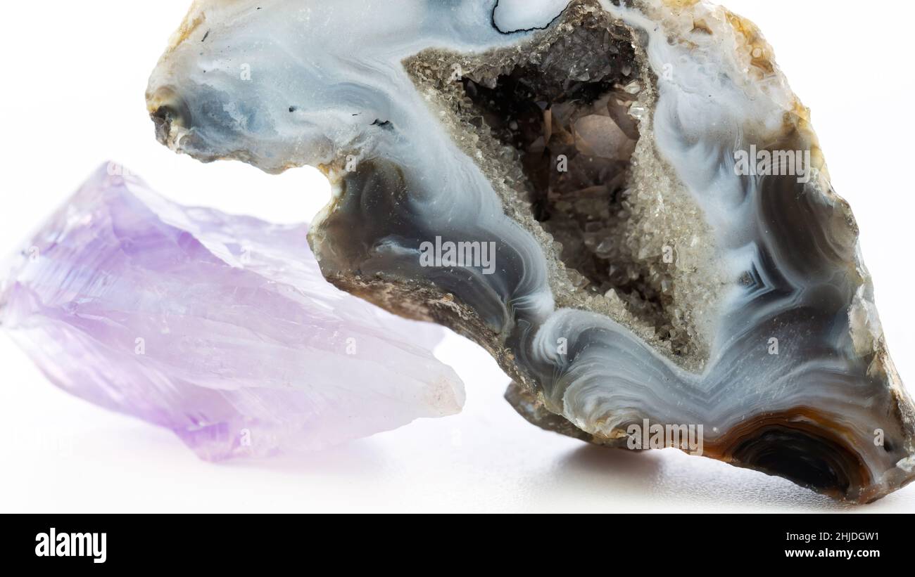 Achat-Geode mit Kristallen und Amethyst-Makrofotografie. Halbedelsteine isoliert auf weißem Hintergrund. Heilende Eigenschaften von Achat und Amethyst Stockfoto