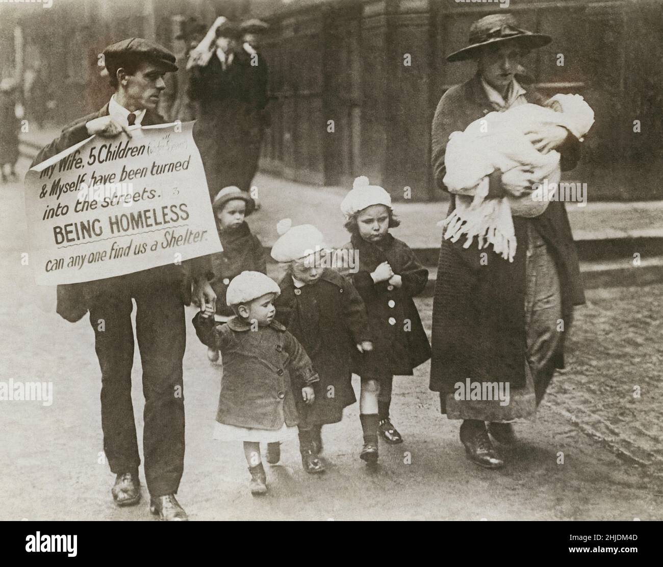 Armut im oktober 1919. Eine Familie wird in London auf der Fleet Street gesehen und der Mann hält ein Schild mit der Aufschrift „Meine Frau, 5 Kinder und ich wurden in die Straßen verwandelt. Als Obdachloser kann uns jemand einen Unterschlupf suchen." Die Mutter trägt ein Kleinkind, und die anderen vier gehen für sich allein. Die Familie, die aus ihrer Wohnung in Kensington London rausgeworfen wird. Montague Channell, Vater und Ehemann und seine Frau Mabel haben ihre Situation in der geschäftigen Zeitung Fleet Street in London mit der Botschaft zum Ausdruck gebracht. Stockfoto