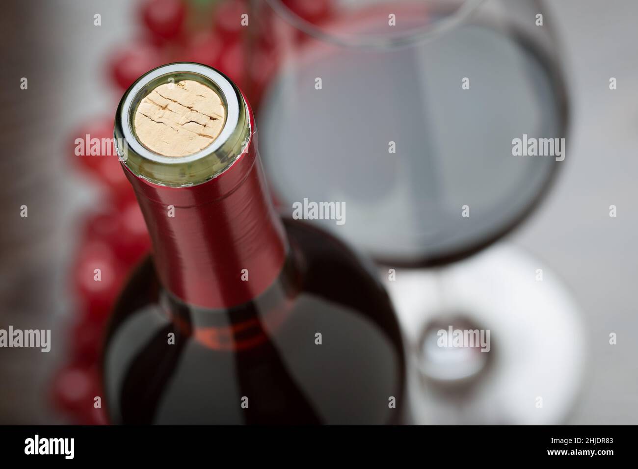 Abstrakte Weinflasche, Kork, Glas und rote Trauben. Stockfoto