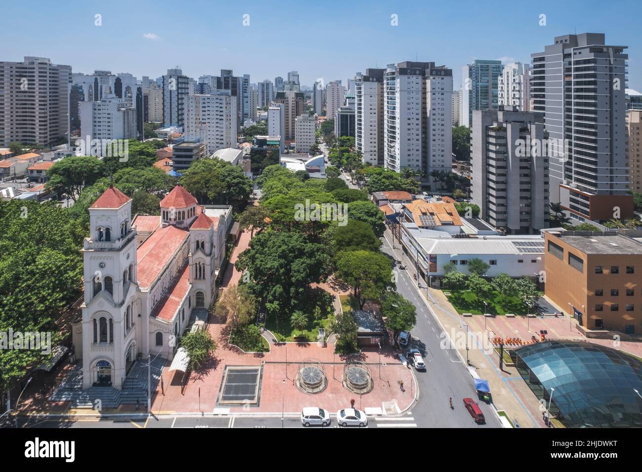 Moema-Viertel, São Paulo, Brasilien. Städtische Skyline des Viertels mit der Kirche Nossa Senhora Aparecida und der Metrostation Moema (Vordergrund) Stockfoto