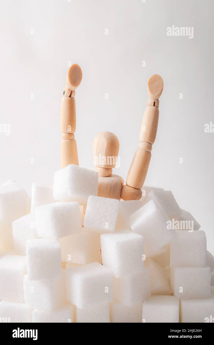 Zuckersucht, Insulinresistenz, ungesunde Ernährung und 14. November ist Diabetes-Bewusstsein Tag Konzept mit einer Marionette Ertrinken in Zuckerwürfeln isoliert o Stockfoto