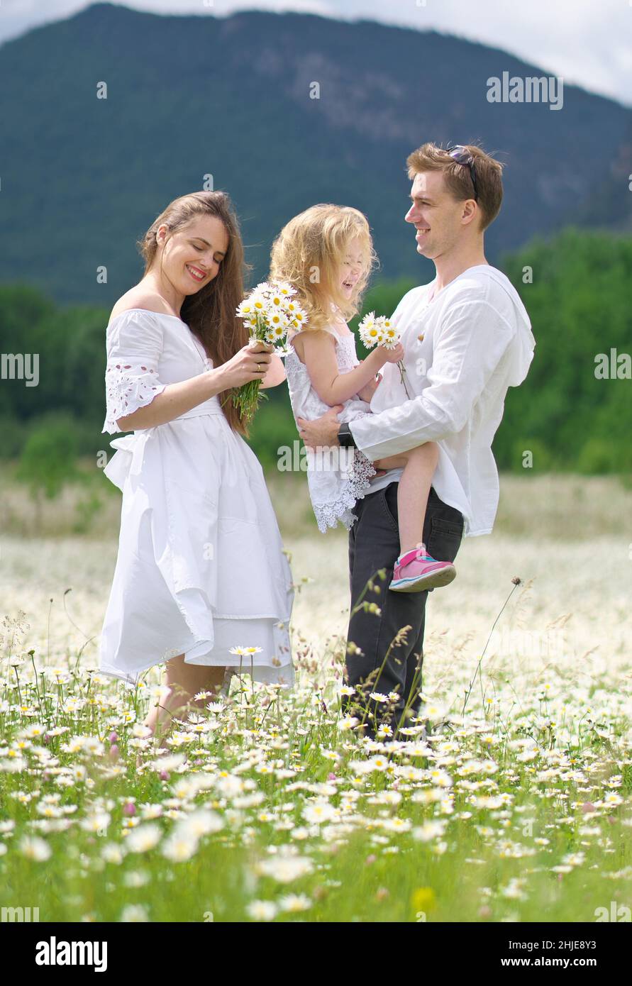 Glückliche Familie auf großer Kamillenwiese. Emotionale, Liebe und Fürsorge Szene. Stockfoto