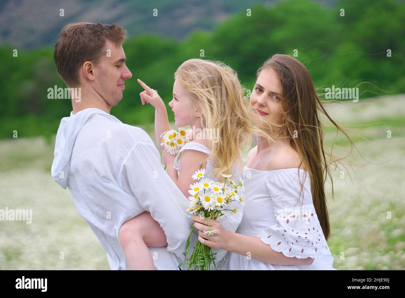 Glückliche Familie auf großer Kamillenwiese. Emotionale, Liebe und Fürsorge Szene. Stockfoto