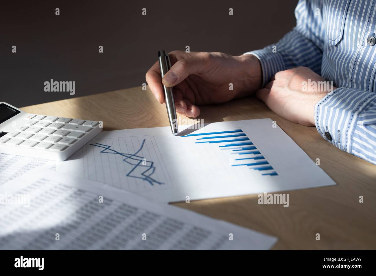 Männliche Hand am Schreibtisch mit Finanzdokument mit Diagramm des wachsenden Trends. Konzept von Wirtschaftswachstum, Einkommenssteigerung und Erfolg. Stockfoto