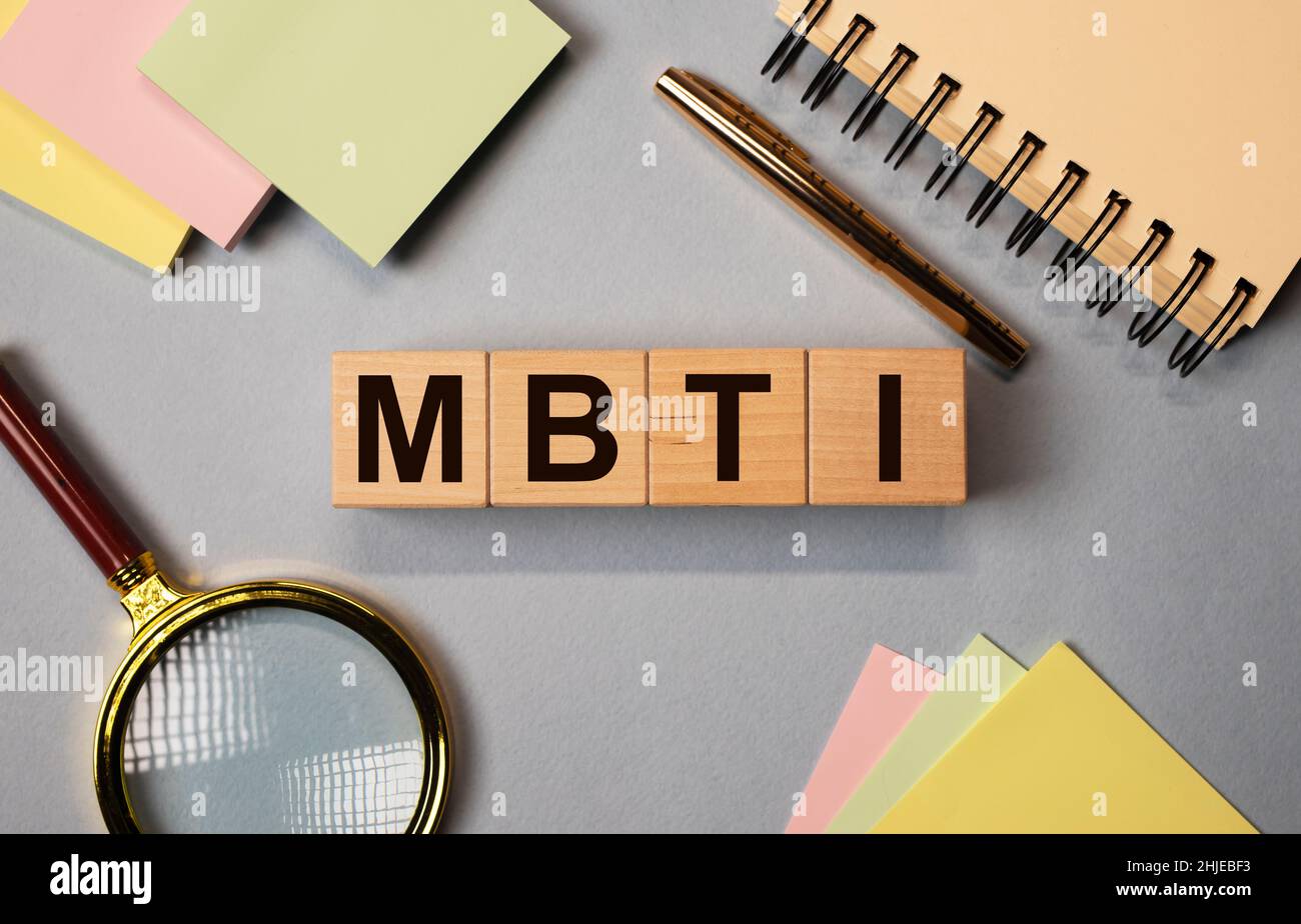 MBTI Akronym, Buchstaben auf Holzdices auf Schreibtisch mit Schreibwaren. Psychologisches Testkonzept. Stockfoto