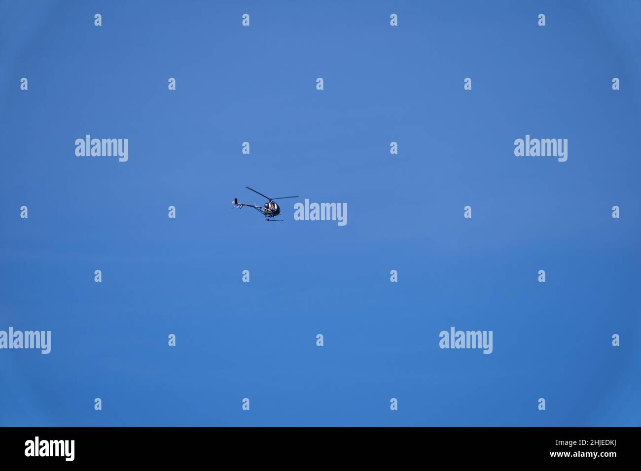 Kleiner Hubschrauber, der gegen den blauen Himmel fliegt Stockfoto