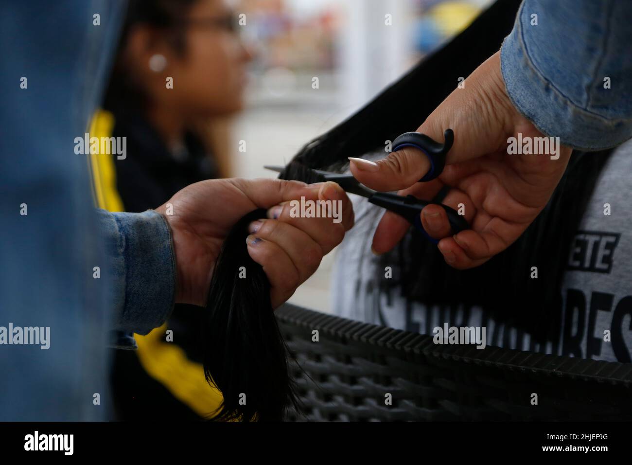 Lima, Peru. 28th Januar 2022. Eine Person lässt sich die Haare abschneiden, um sie zu spenden. Nach der Ölpest an den Stränden von Ventanilla ist eine Kampagne im Gange, um menschliche und tierische Haare zu sammeln, um bei den Dekontaminationsarbeiten im Meer zu helfen. Das Haar wird verwendet, um Filter zu machen, um das Öl aufzusaugen. Beim Entladen eines Tankers in der Raffinerie La Pampilla des spanischen Energiekonzerns Repsol waren große Mengen Öl ausgetreten. Kredit: Gian Masko/dpa/Alamy Live Nachrichten Stockfoto