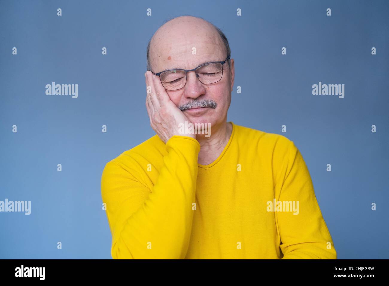 Älterer Mann in Brille schläft müde und träumt lächelnd mit geschlossenen Augen. Studioaufnahme Stockfoto