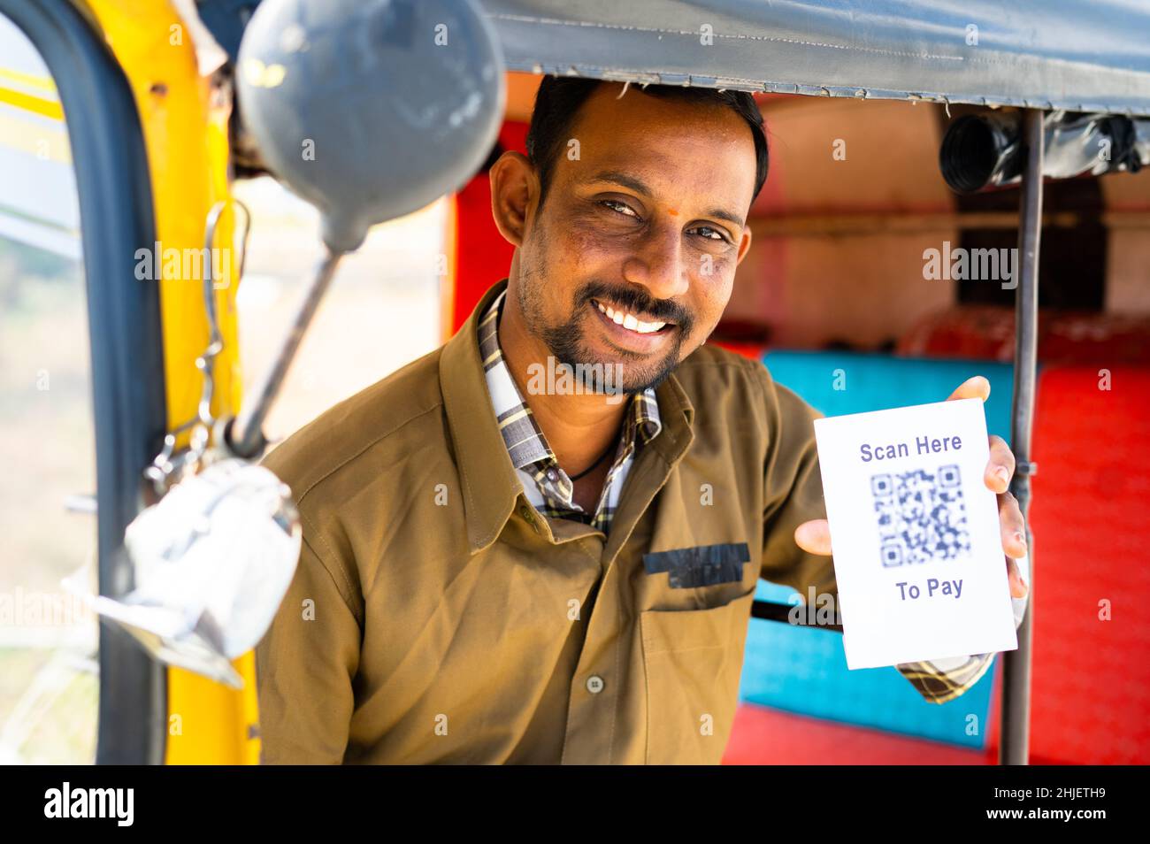 Lächelnder Autofahrer, der QR- oder Barcode-Scanner für den kontektlosen E-Payment mit Blick auf die Kamera zeigt – Konzept der bargeldlosen digitalen Zahlungsempfehlung. Stockfoto