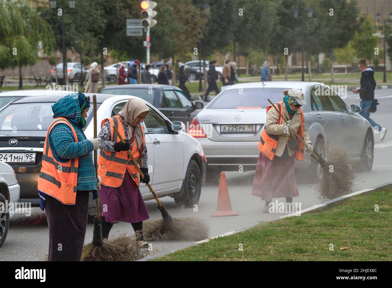 GROSNY, RUSSLAND - 29. SEPTEMBER 2021: Tschetschenische Frauen fegen die Straße der Stadt. Kommunale Reinigung der Stadt Stockfoto