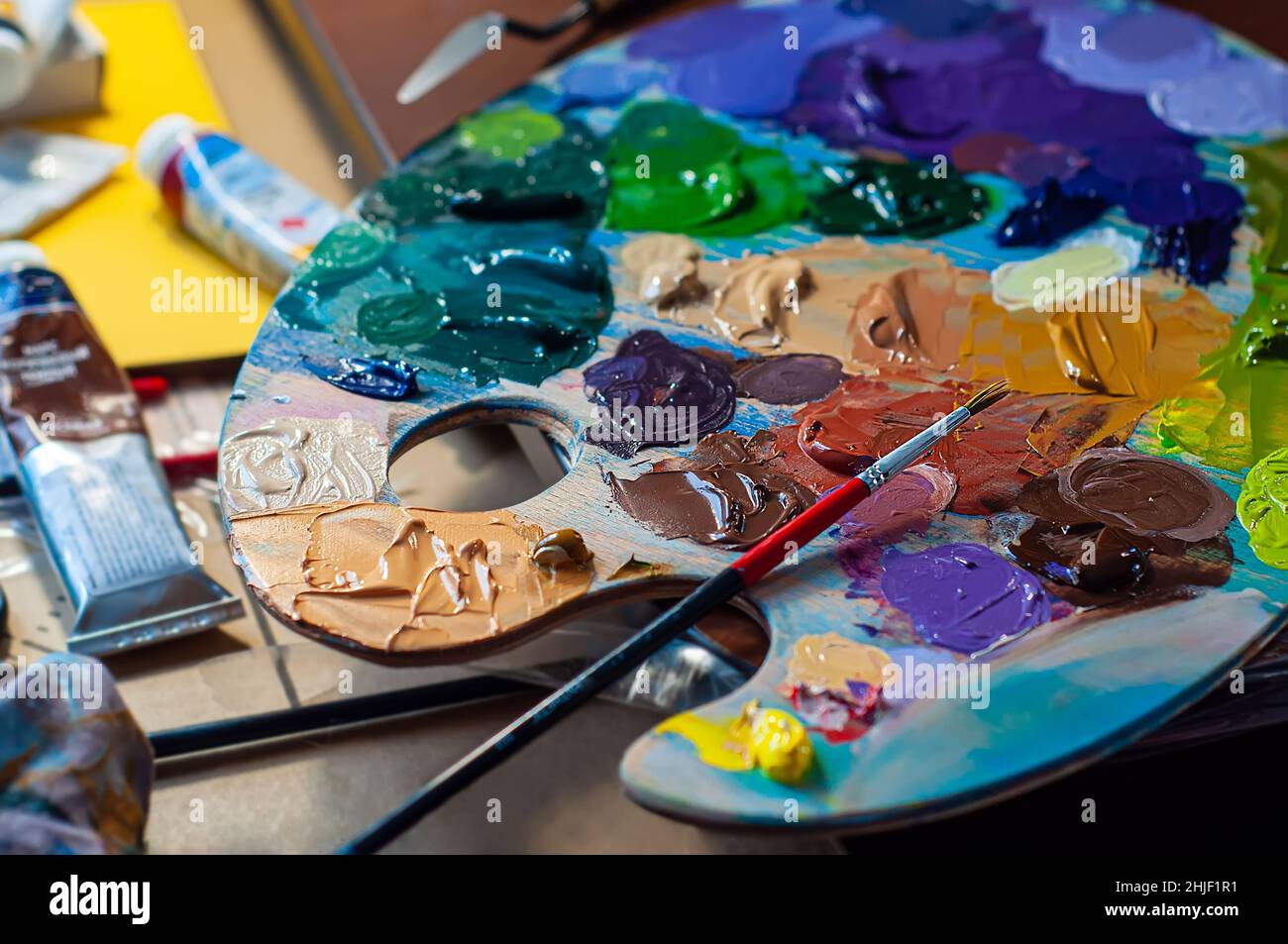 Palette mit Ölfarben und einem Pinsel. Malprozess, Kunstwerkstatt. Verschiedene Farbfarben werden zum Mischen aufgetragen. Stockfoto