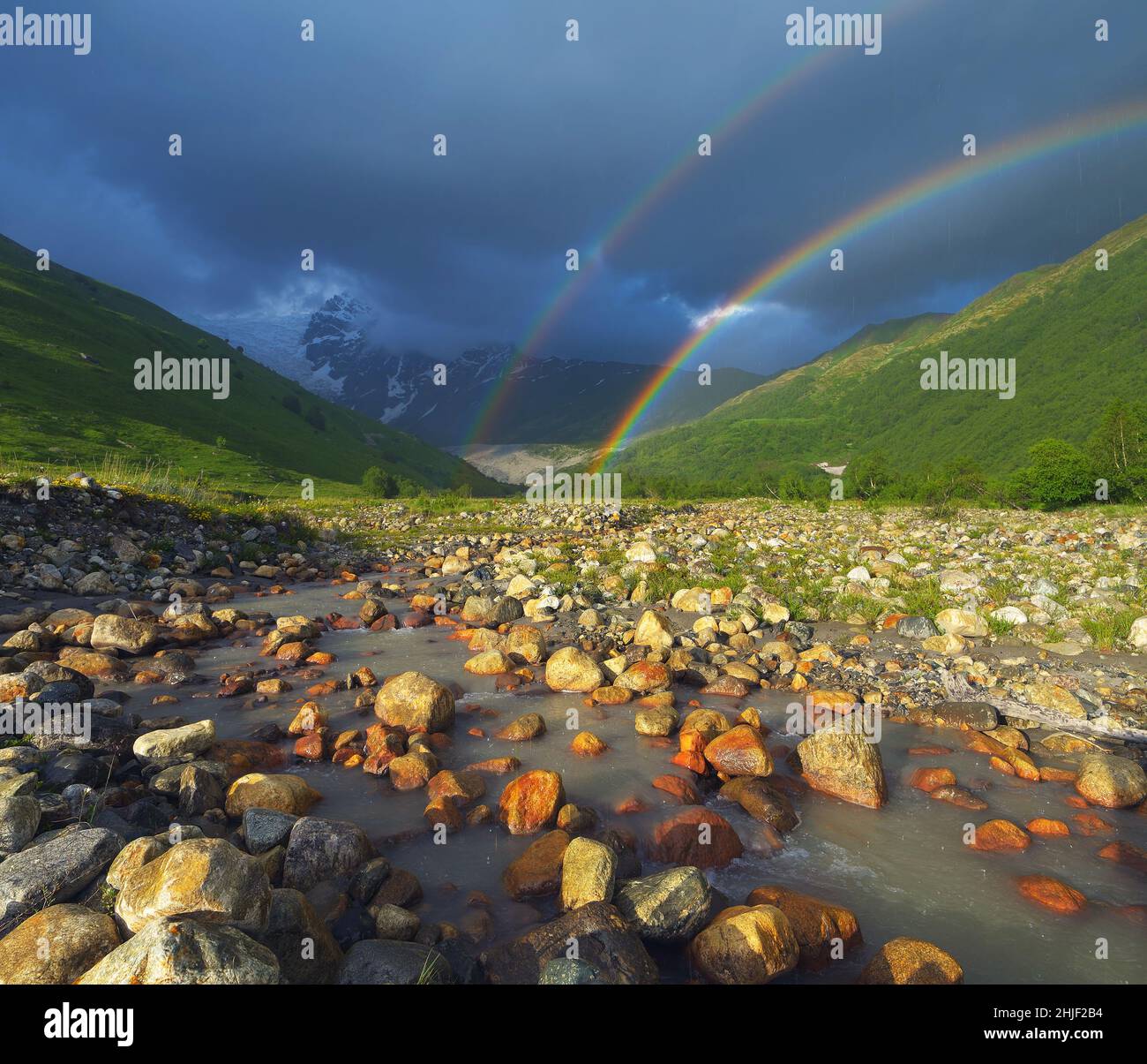 Sommer Landschaft mit Regenbogen in den Bergen über dem Fluss. Zemo Swanetien, Georgien Stockfoto