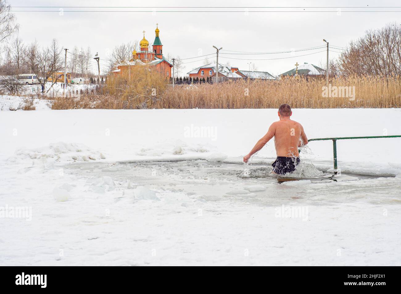 Poltawa, Ukraine. Januar 19. 2022. Ein Mensch steigt im Winter, dem Fest der Epiphany, ins Wasser herab. Orthodoxe Wintertraditionen, Schwimmen in einem Loch Stockfoto