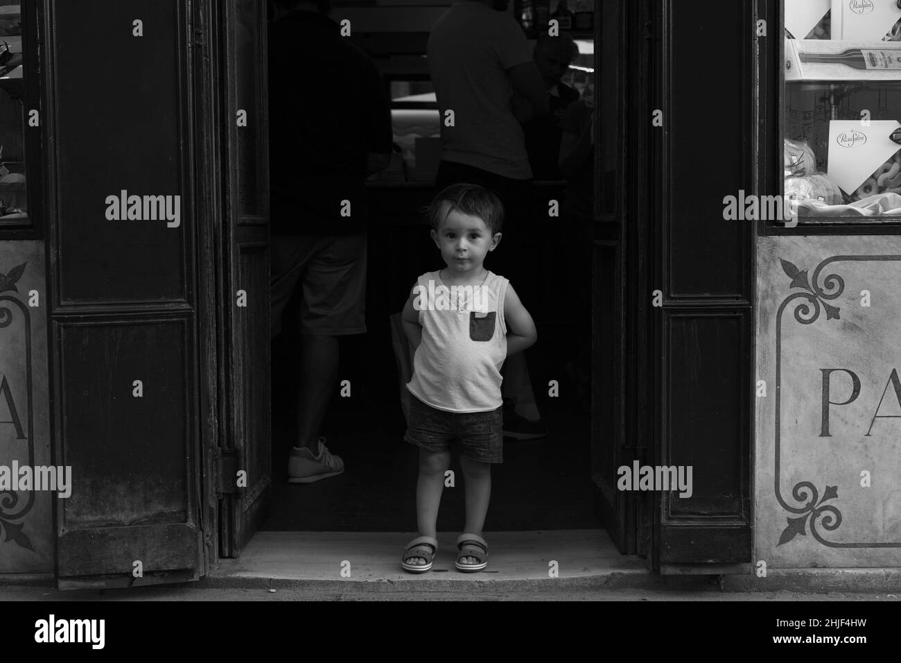 Porträt eines kleinen Kindes vor einem typischen Geschäft in Venedig, Italien. Schwarz-Weiß-Vintage-Foto Stockfoto