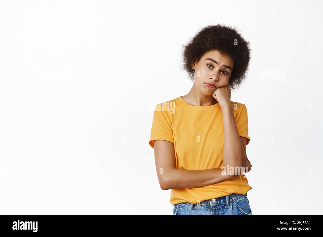 Junge traurige afrikanische Frau, die gelangweilt oder unamüsiert aussieht, widerstrebendes verstörtes Gesicht, düstere Emotionen, die über weißem Hintergrund stehen Stockfoto