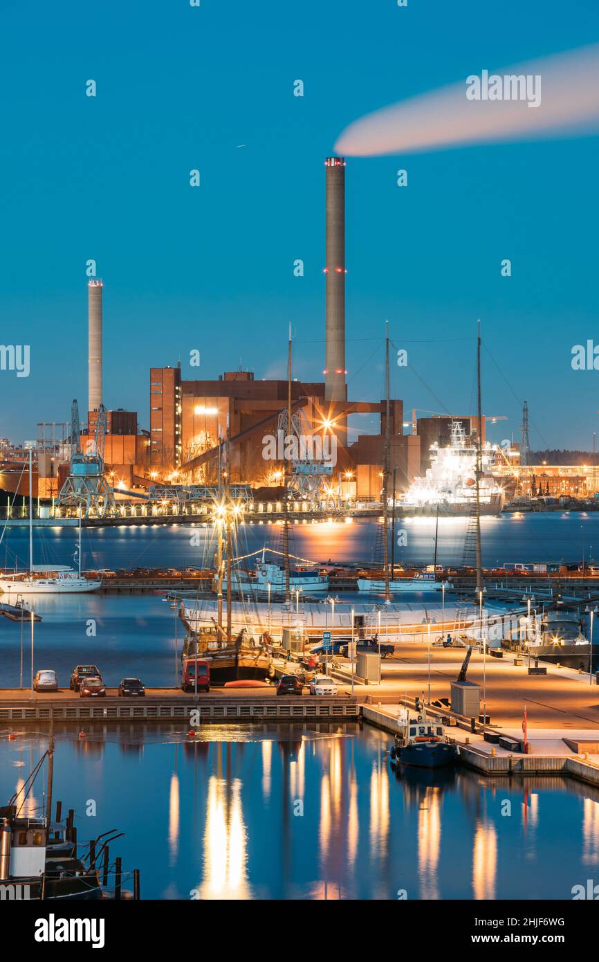 Helsinki, Finnland. Nachtansicht Der Industriezone Des Hanasaari Kraftwerks Und Pier, Liegeplatz Mit Festfahrenden Schiffen, Schiffen. Nachtbeleuchtung Stockfoto