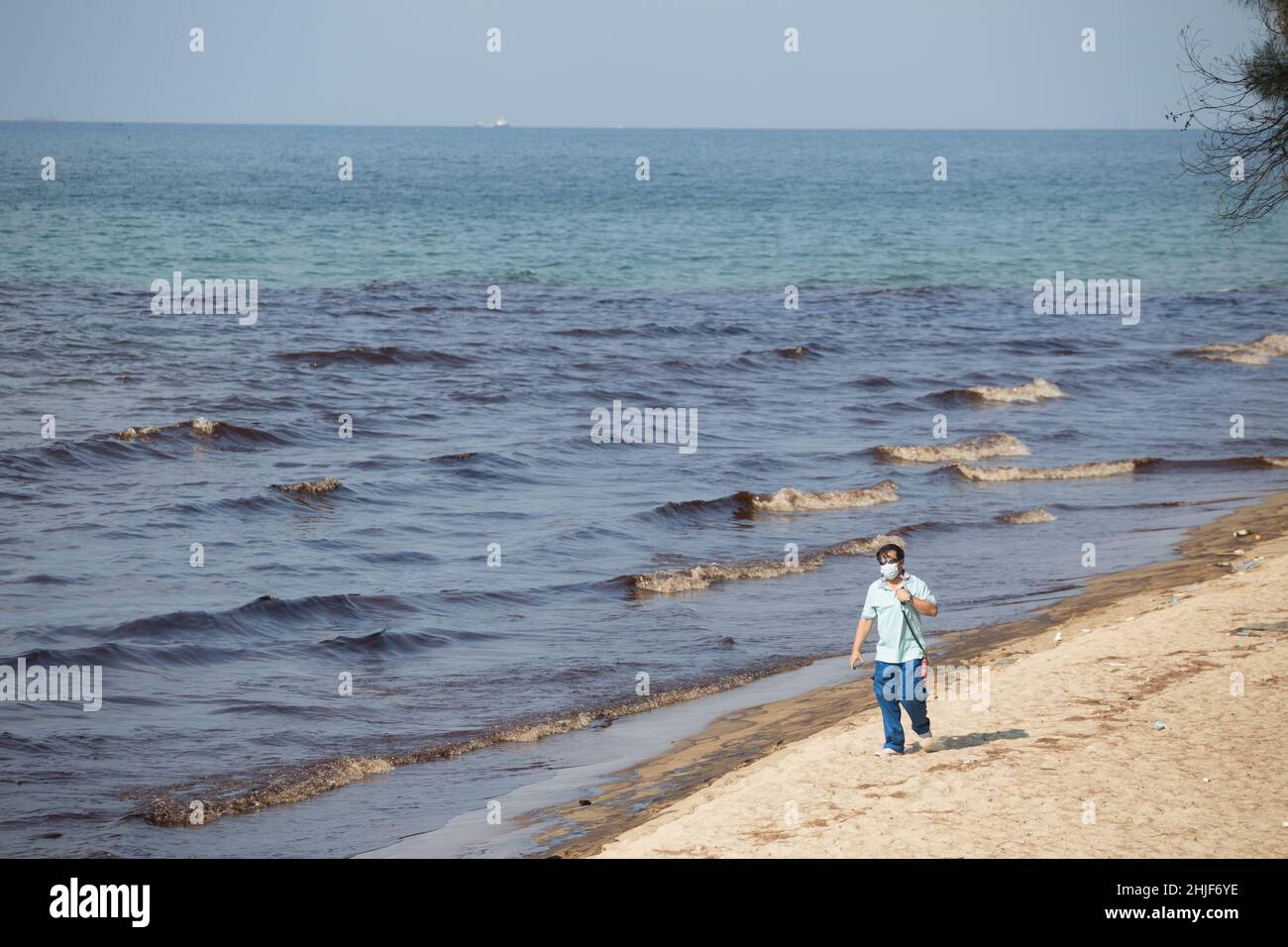 Rayong, Thailand. 29th Januar 2022. Ein Tourist kommt an einem Rohöl vorbei, das an einem Strand verschüttet wird.Beamte der Provinz Rayong eilten, um Rohölflecken am Strand zu beseitigen. Nach einem Ölpipeline-Leck unter dem Meer in der Provinz Rayong, Mae Ramphueng Beach Thailand. Kredit: SOPA Images Limited/Alamy Live Nachrichten Stockfoto